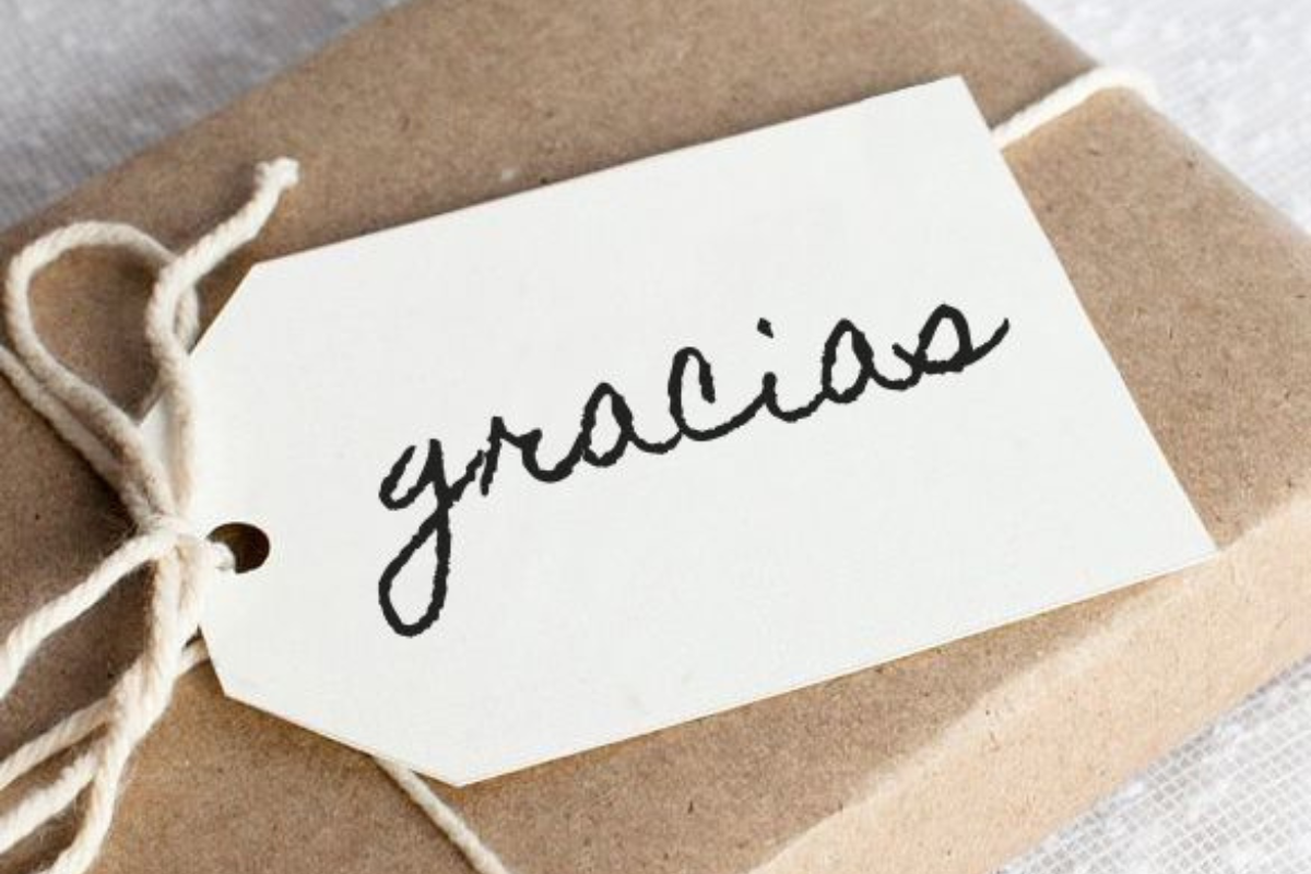 Etiqueta con la palabra "gracias" sobre un regalo envuelto, simbolizando el poder del agradecimiento y la gratitud cotidiana.